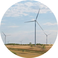 An image of wind turbines in a field with a blue sky and wispy clouds.